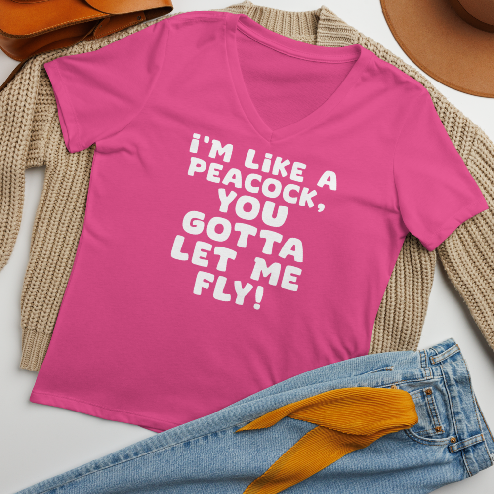 "I'm like a peacock, you gotta let me fly!" printed on a berry women's relaxed v-neck t-shirt laying on a flat surface amongst other clothes