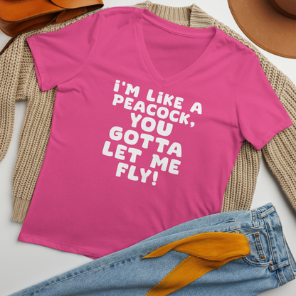 "I'm like a peacock, you gotta let me fly!" printed on a berry women's relaxed v-neck t-shirt laying on a flat surface amongst other clothes