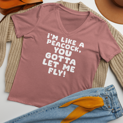 "I'm like a peacock, you gotta let me fly!" printed on a heather mauve women's relaxed v-neck t-shirt laying on a flat surface amongst other clothes