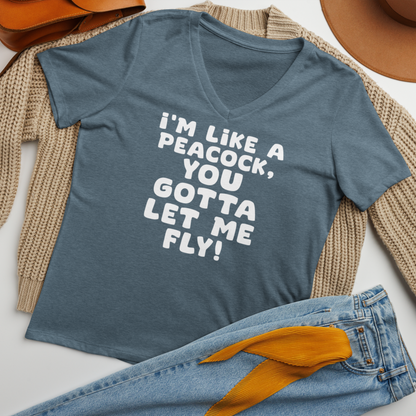 "I'm like a peacock, you gotta let me fly!" printed on a heather slate women's relaxed v-neck t-shirt laying on a flat surface amongst other clothes