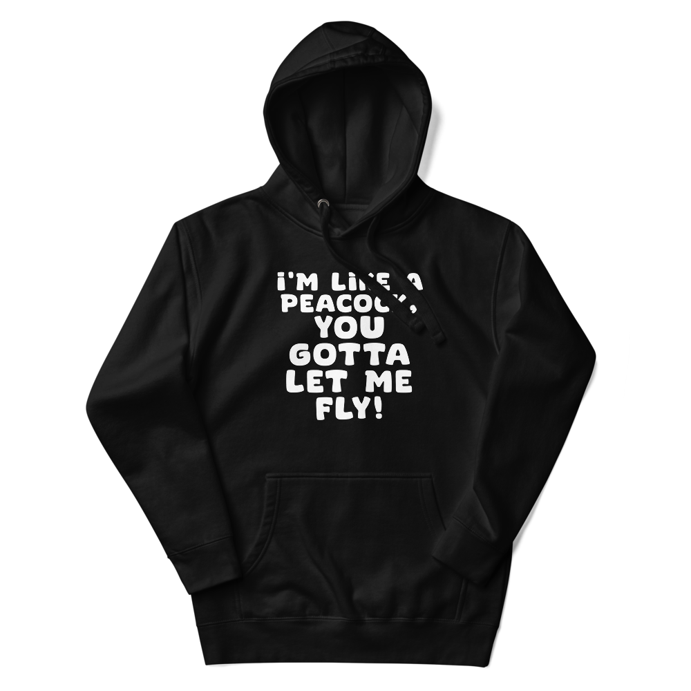 "I'm like a peacock, you gotta let me fly!" printed on a black unisex hoodie laying on a flat surface with the hood up