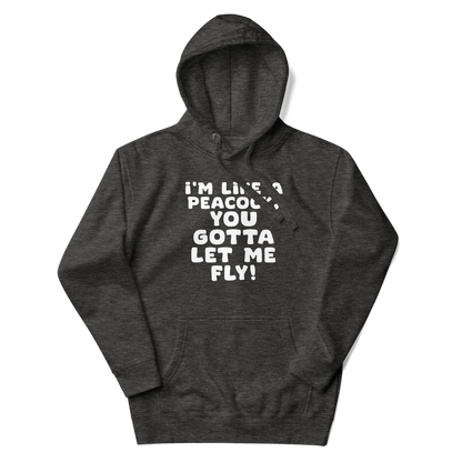 "I'm like a peacock, you gotta let me fly!" printed on a charcoal heather unisex hoodie laying on a flat surface with the hood up