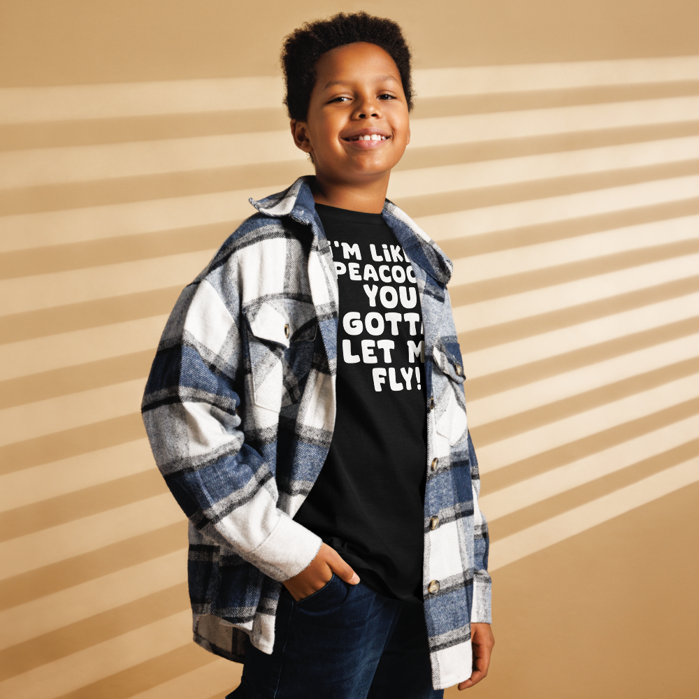 "I'm like a peacock, you gotta let me fly!" printed on a black youth classic tee worn by a male also wearing a jacket