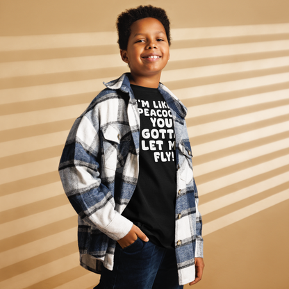 "I'm like a peacock, you gotta let me fly!" printed on a black youth classic tee worn by a male also wearing a jacket