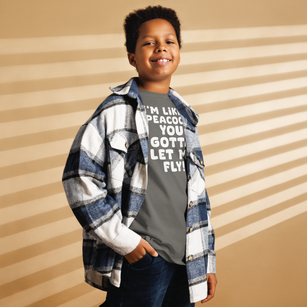 "I'm like a peacock, you gotta let me fly!" printed on a charcoal youth classic tee worn by a male also wearing a jacket