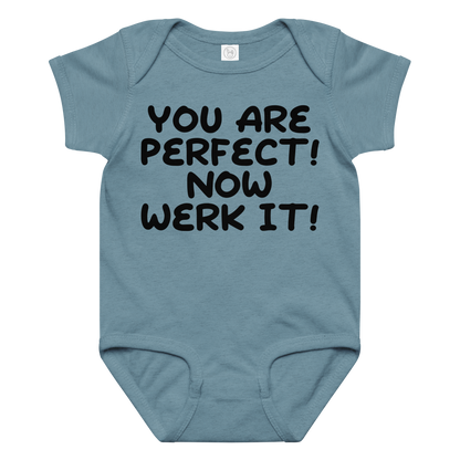 "You Are Perfect! Now Werk It!" printed on a vintage indigo baby jersey bodysuit laying on a flat surface amongst other clothes