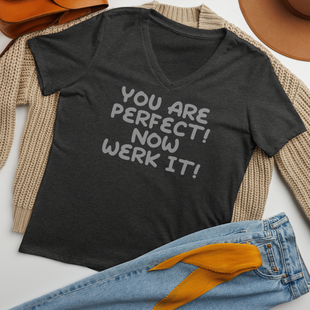 "You Are Perfect! Now Werk It!" printed on a dark grey heather women's relaxed v-neck t-shirt laying on a flat surface amongst other clothes