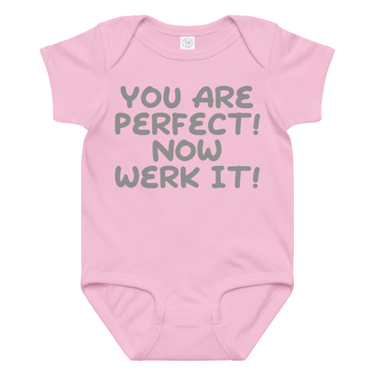 "You Are Perfect! Now Werk It!" printed on a pink baby jersey bodysuit laying on a flat surface amongst other clothes