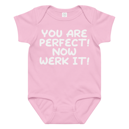 "You Are Perfect! Now Werk It!" printed on a pink baby jersey bodysuit laying on a flat surface amongst other clothes
