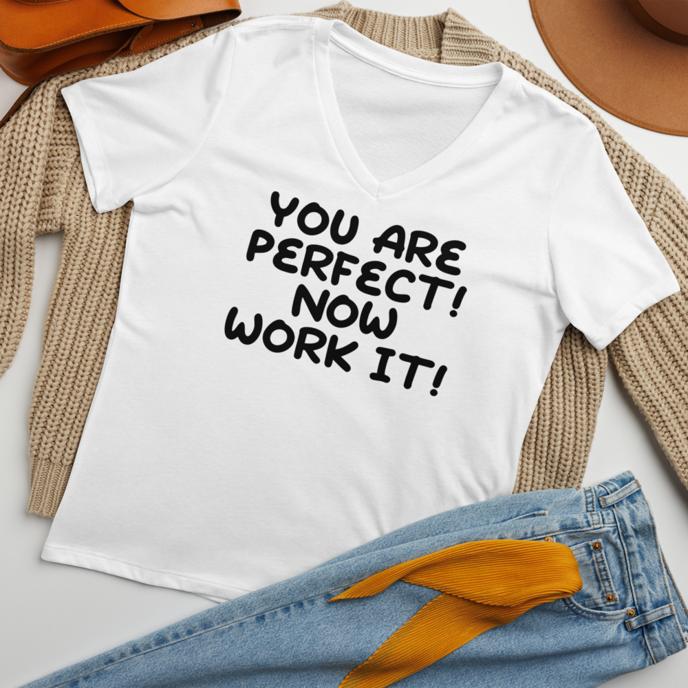 "You Are Perfect! Now Work It!" printed on a solid white blend women's relaxed v-neck t-shirt laying on a flat surface amongst other clothes