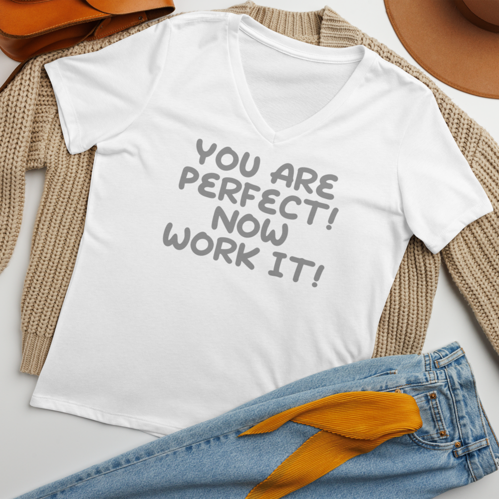 "You Are Perfect! Now Work It!" printed on a solid white blend women's relaxed v-neck t-shirt laying on a flat surface amongst other clothes