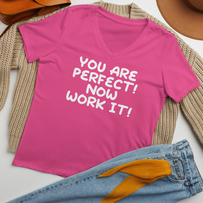 "You Are Perfect! Now Work It!" printed on a berry women's relaxed v-neck t-shirt laying on a flat surface amongst other clothes