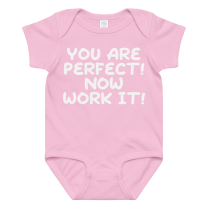 "You Are Perfect! Now Work It!" printed on a pink baby jersey bodysuit laying on a flat surface amongst other clothes