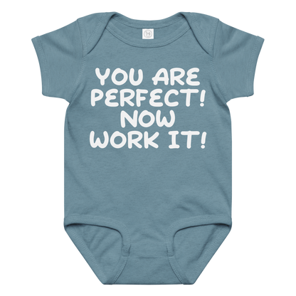 "You Are Perfect! Now Work It!" printed on a vintage indigo baby jersey bodysuit laying on a flat surface amongst other clothes