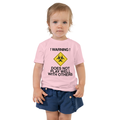 "!Warning! Does Not Play Well With Others" printed on a pink toddler short sleeve tee worn by a female