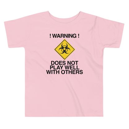 "!Warning! Does Not Play Well With Others" printed on a pink toddler short sleeve tee laying on a flat surface
