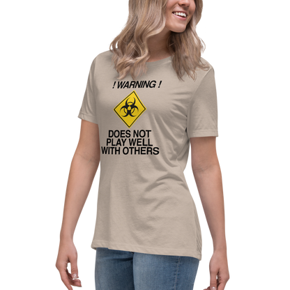 "!Warning! Does Not Play Well With Others" printed on a heather stone women's relaxed t-shirt worn by a female