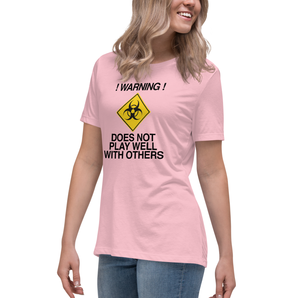 "!Warning! Does Not Play Well With Others" printed on a pink women's relaxed t-shirt worn by a female