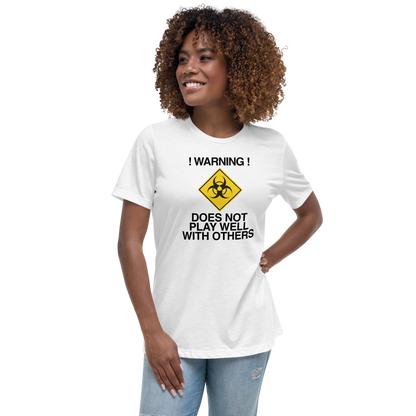 "!Warning! Does Not Play Well With Others" printed on a white women's relaxed t-shirt worn by a female