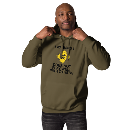 "!Warning! Does Not Play Well With Others" printed on a military green unisex hoodie worn by a male