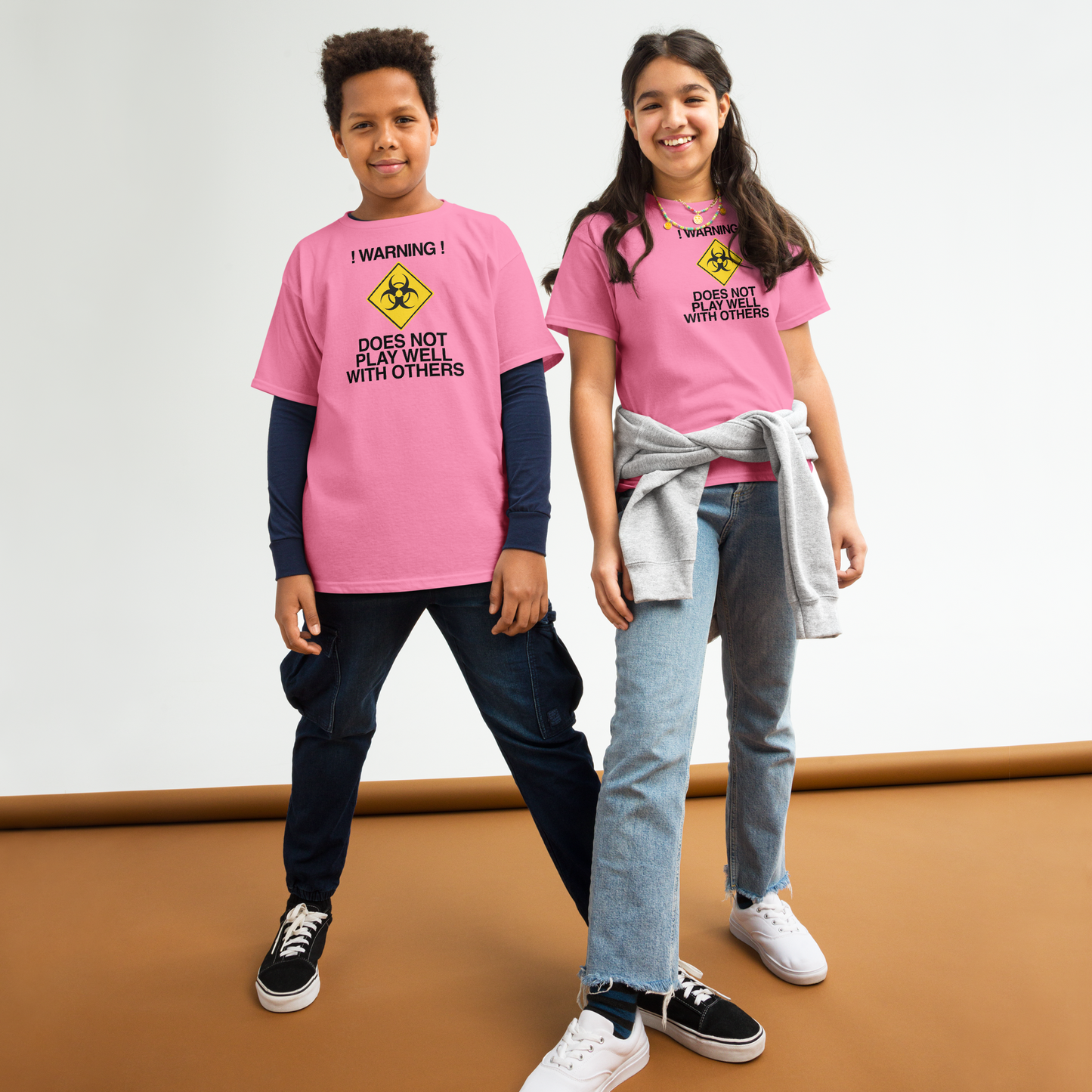 "!Warning! Does Not Play Well With Others" printed on a azalea youth classic tee worn by a female and male