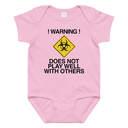 "!Warning! Does Not Play Well With Others" printed on a pink baby jersey bodysuit laying on a flat surface amongst other clothes