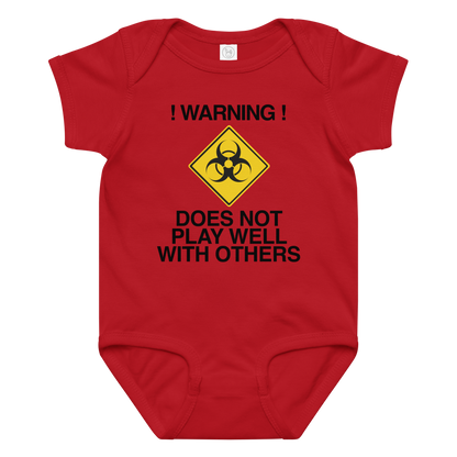 "!Warning! Does Not Play Well With Others" printed on a red baby jersey bodysuit laying on a flat surface amongst other clothes