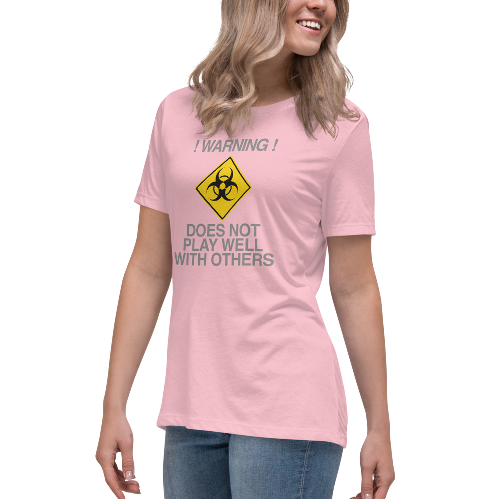 "!Warning! Does Not Play Well With Others" printed on a pink women's relaxed t-shirt worn by a female