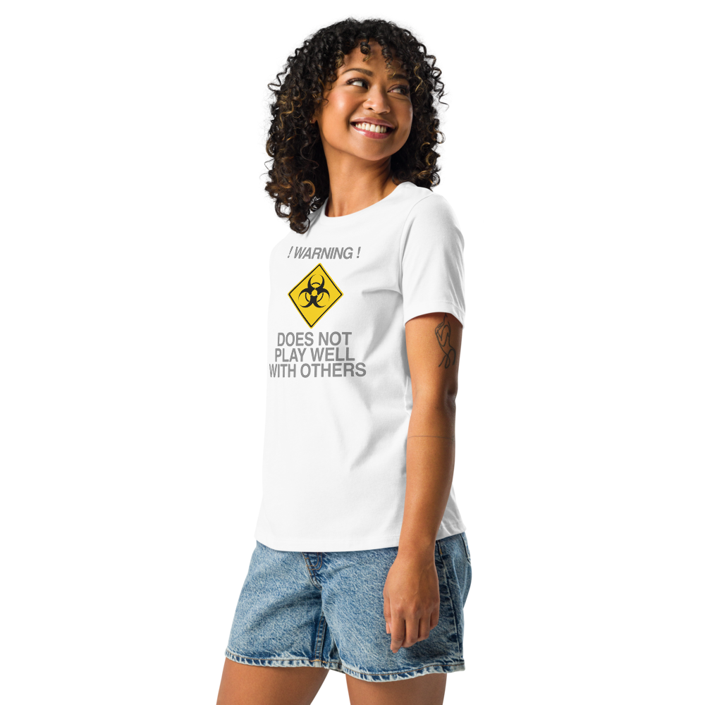 "!Warning! Does Not Play Well With Others" printed on a white women's relaxed t-shirt worn by a female