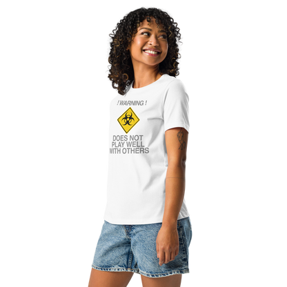 "!Warning! Does Not Play Well With Others" printed on a white women's relaxed t-shirt worn by a female