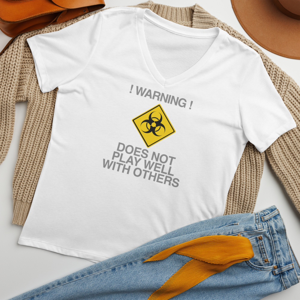 "!Warning! Does Not Play Well With Others" printed on a solid white blend women's relaxed v-neck t-shirt laying on a flat surface amongst other clothes