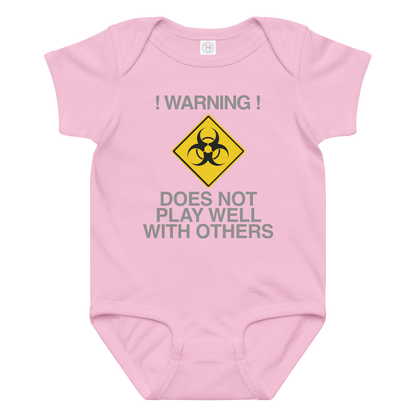 "!Warning! Does Not Play Well With Others" printed on a pink baby jersey bodysuit laying on a flat surface amongst other clothes