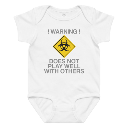 "!Warning! Does Not Play Well With Others" printed on a white baby jersey bodysuit laying on a flat surface amongst other clothes
