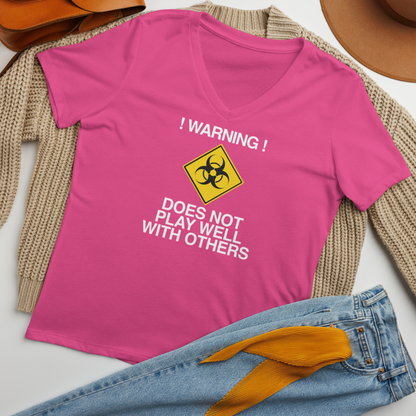 "!Warning! Does Not Play Well With Others" printed on a berry women's relaxed v-neck t-shirt laying on a flat surface amongst other clothes