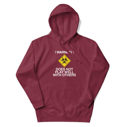 "!Warning! Does Not Play Well With Others" printed on a maroon unisex hoodie laying on a flat surface with the hood up