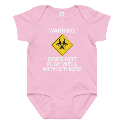 "!Warning! Does Not Play Well With Others" printed on a pink baby jersey bodysuit laying on a flat surface amongst other clothes