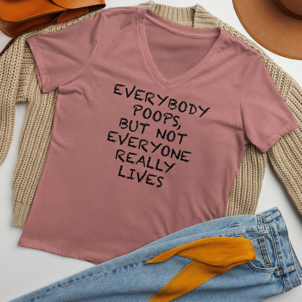 "Everybody poops, but not everyone really lives" printed on a heather mauve women's relaxed v-neck t-shirt laying on a flat surface amongst other clothes
