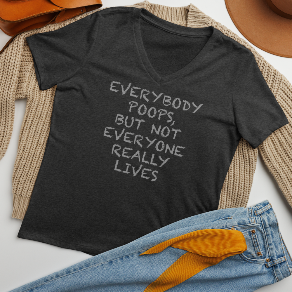 "Everybody poops, but not everyone really lives" printed on a dark grey heather women's relaxed v-neck t-shirt laying on a flat surface amongst other clothes