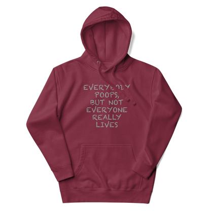 "Everybody poops, but not everyone really lives" printed on a maroon unisex hoodie laying on a flat surface with the hood up