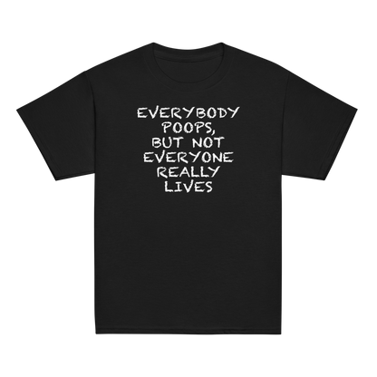 "Everybody poops, but not everyone really lives" printed on a black youth classic tee laying on a flat surface