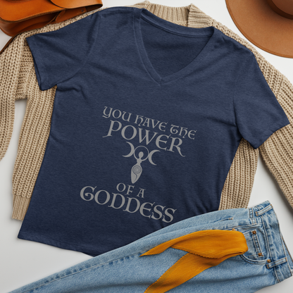 "You have the power of a goddess" printed on a heather navy women's relaxed v-neck t-shirt laying on a flat surface amongst other clothes