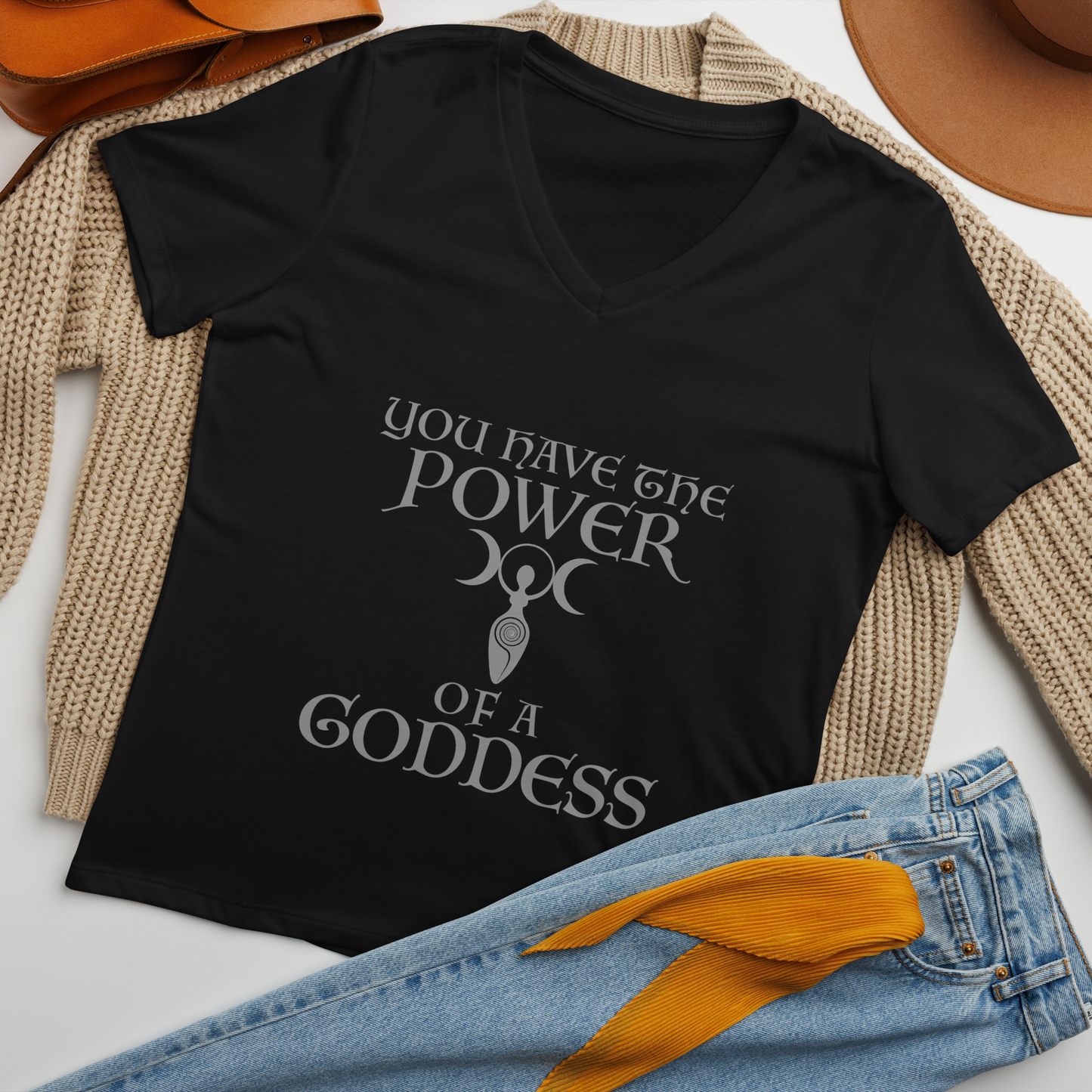 "You have the power of a goddess" printed on a solid black blend women's relaxed v-neck t-shirt laying on a flat surface amongst other clothes