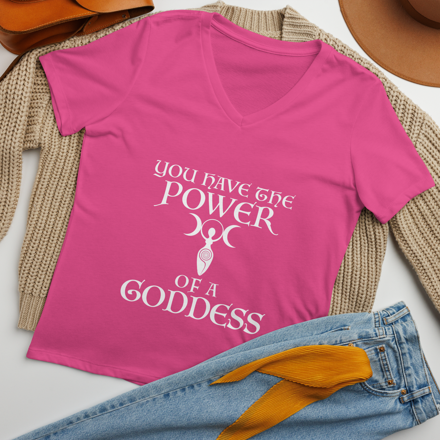 "You have the power of a goddess" printed on a berry women's relaxed v-neck t-shirt laying on a flat surface amongst other clothes