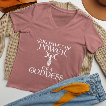 "You have the power of a goddess" printed on a heather mauve women's relaxed v-neck t-shirt laying on a flat surface amongst other clothes
