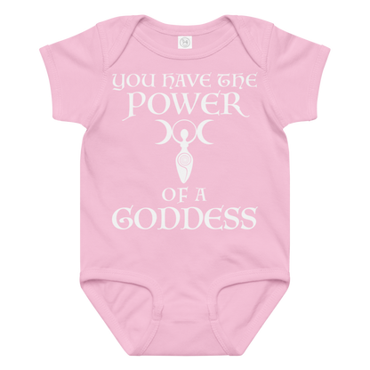 "You have the power of a goddess" printed on a pink baby jersey bodysuit laying on a flat surface amongst other clothes