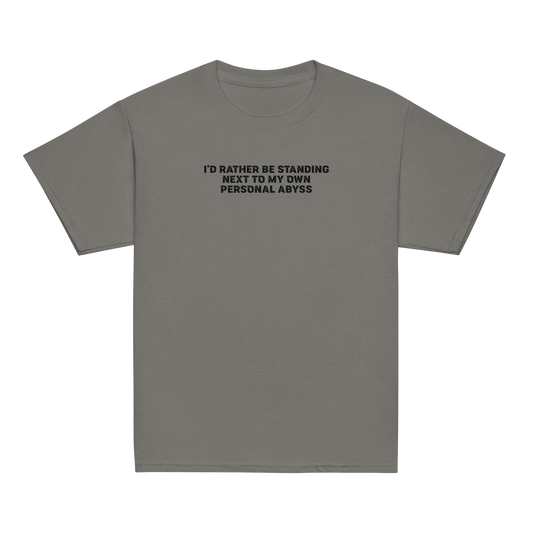 "I'd rather be standing next to my own personal abyss" printed on a charcoal youth classic tee laying on a flat surface