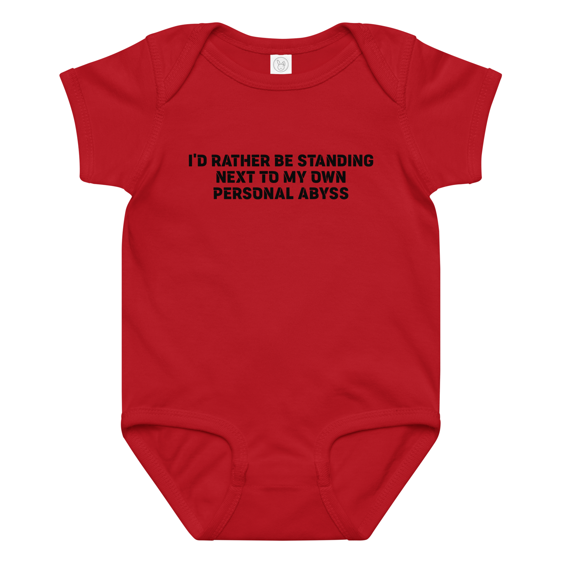 "I'd rather be standing next to my own personal abyss" printed on a red baby jersey bodysuit laying on a flat surface amongst other clothes