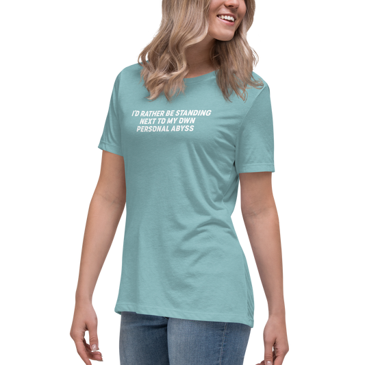 "I'd rather be standing next to my own personal abyss" printed on a heather blue lagoon women's relaxed t-shirt worn by a female