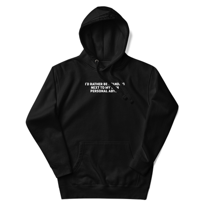 "I'd rather be standing next to my own personal abyss" printed on a black unisex hoodie laying on a flat surface with the hood up