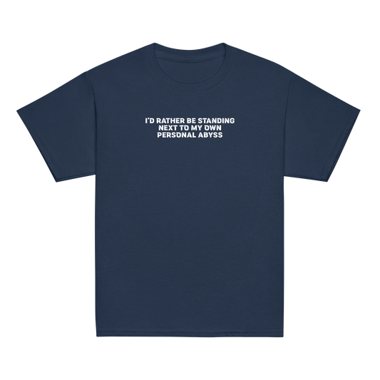 "I'd rather be standing next to my own personal abyss" printed on a navy youth classic tee laying on a flat surface